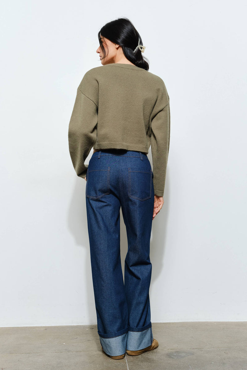 Cropped olive green sweater with a relaxed fit and ribbed details, paired with wide-leg denim jeans, reflects Long Island boutique fashion.