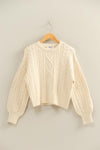 Cream-colored cable knit balloon sleeve sweater with ribbed cuffs and a relaxed fit, perfect for cozy Long Island boutique fashion.