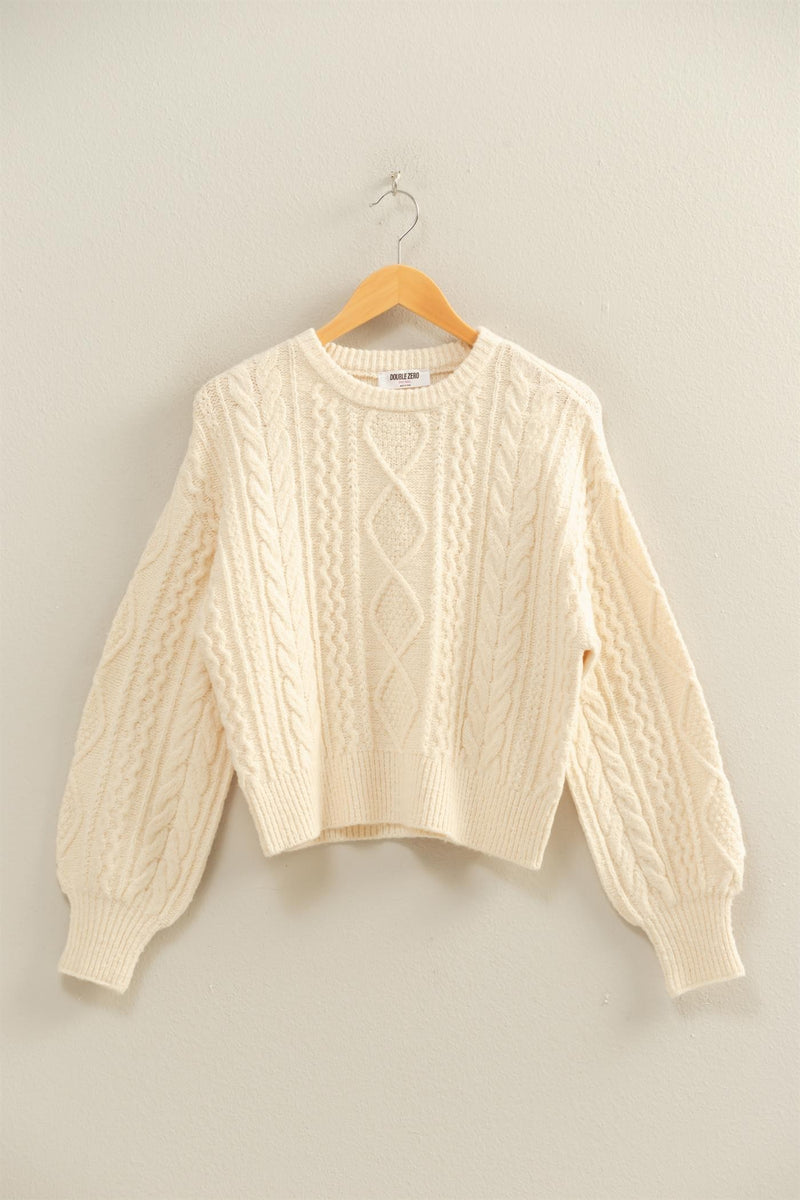 Cream-colored cable knit balloon sleeve sweater with ribbed cuffs and a relaxed fit, perfect for cozy Long Island boutique fashion.