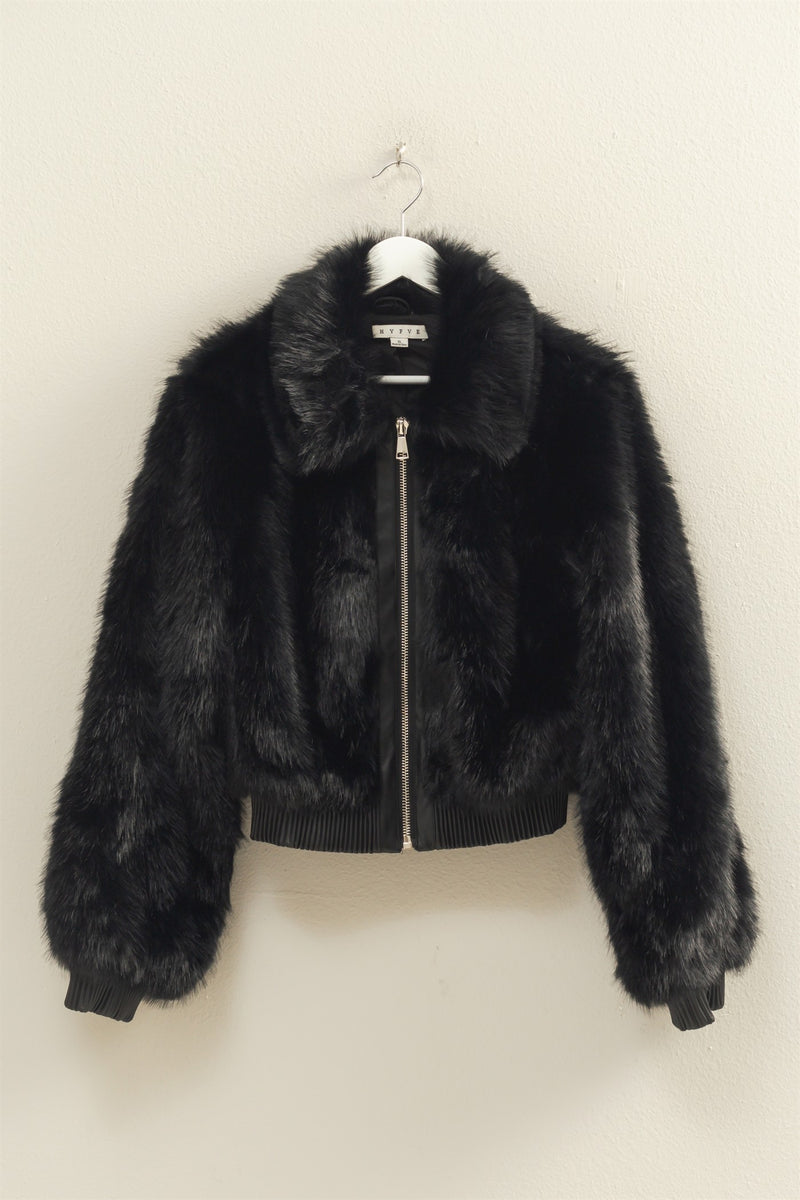 Plush black faux fur zippered jacket with a cropped fit and ribbed cuffs, perfect for chic Long Island boutique fashion.