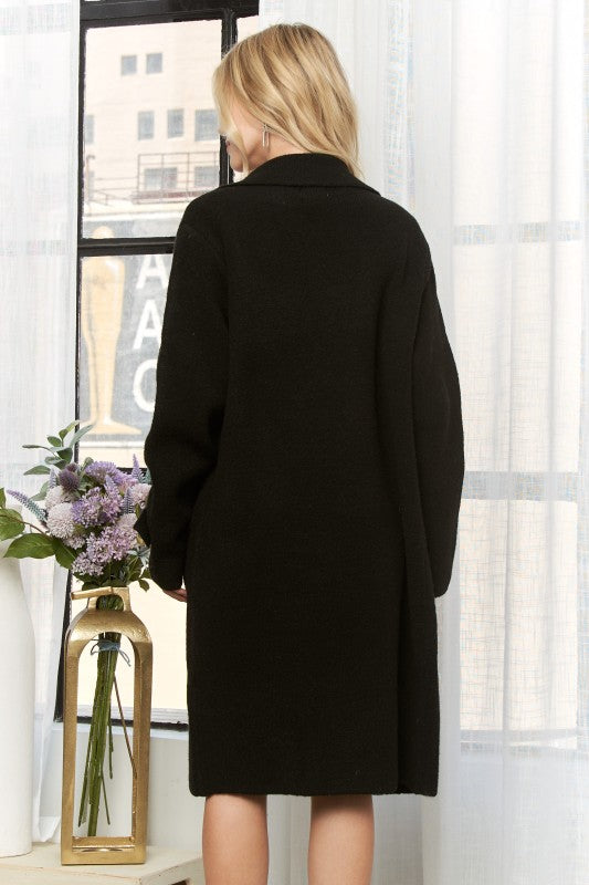 Classic longline coat in black featuring chic button detailing and a relaxed fit, perfect for Long Island boutique fashion.