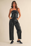 Striking faux leather barrel strapless jumpsuit in sleek black, featuring a fitted bodice and wide-leg pant style, perfect for contemporary Long Island boutique fashion.