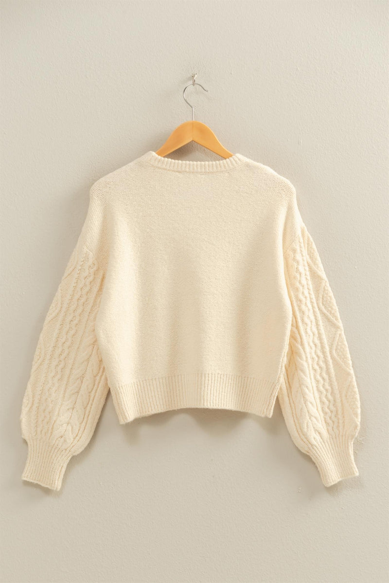 Cream cable knit balloon sleeve sweater with a cozy cropped fit, perfect for adding texture to your Long Island boutique fashion wardrobe.