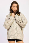 Oversized camo trucker jacket in muted tones features a beige and green pattern, complemented by a contrasting collar, perfect for Long Island boutique fashion.