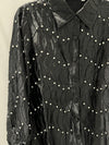 This black embellished blouse top features a textured wavy pattern, shiny fabric, and decorative pearl-like accents, perfect for Long Island boutique fashion.