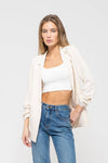 Light beige 3/4 ruched sleeve blazer paired with a fitted white crop top and high-waisted denim, perfect for Long Island boutique fashion.