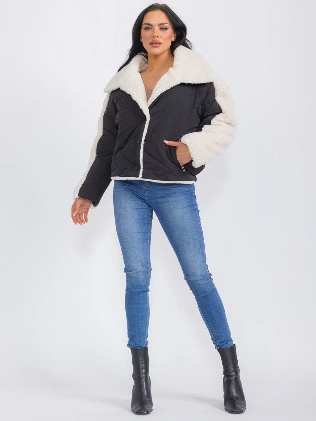 Woman wearing a black jacket with white fur collar and blue jeans on a white background
