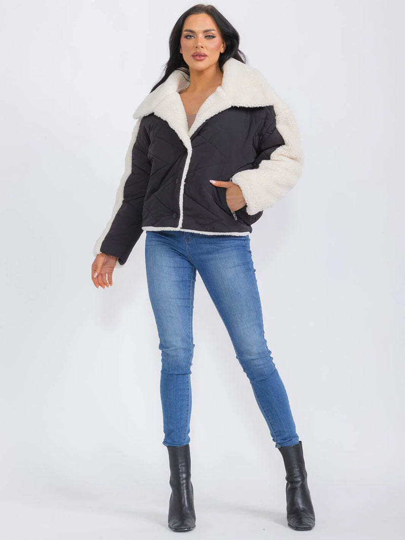 Woman wearing a black jacket with white fur collar and blue jeans on a white background