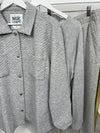 Gray textured shirt and pants on hangers with a visible brand label.