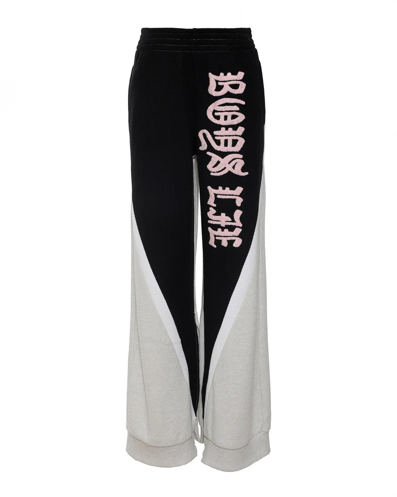 High-waisted black and gray wide-leg pants featuring bold pink "Boys Lie" lettering, perfect for chic Long Island boutique fashion.