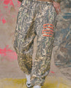 Camo patterned jogger pants featuring an elastic waistband and bold red text, perfect for casual wear from a Long Island fashion boutique.
