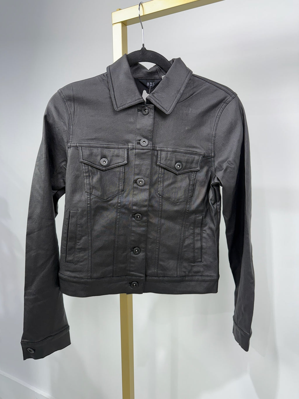 Coated black denim jacket with a fitted silhouette, button front, and chest pockets, perfect for Long Island boutique fashion styling.