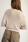 Cropped knit sweater in soft beige features half dolman sleeves and a relaxed fit, ideal for contemporary Long Island boutique fashion.