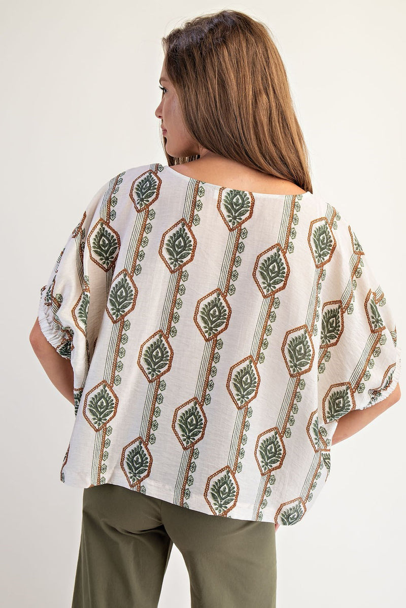 Flowy white blouse featuring a geometric floral print in green and rust, with elastic cuffs, perfect for Long Island boutique fashion.
