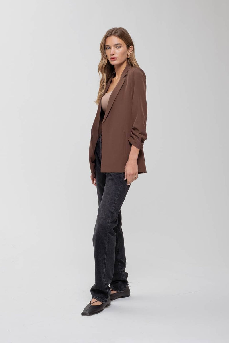 Chic brown 3/4 ruched sleeve blazer paired with black jeans, perfect for stylish ensembles from a Long Island fashion boutique.