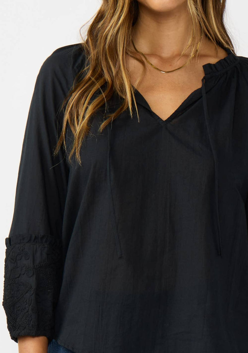 Flowy black blouse featuring frilled sleeves and a split neck, perfect for adding a touch of elegance to your Long Island boutique fashion wardrobe.