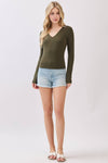 Fitted double layer long sleeve V-neck top in olive green, paired with light denim shorts, perfect for Long Island boutique fashion.