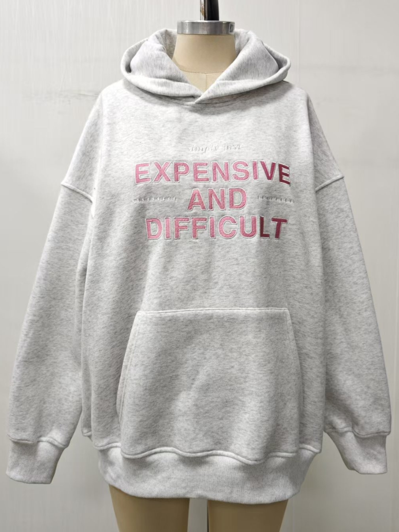 Cozy grey hoodie featuring bold embroidered text "EXPENSIVE AND DIFFICULT," perfect for casual wear from a Long Island women’s boutique.