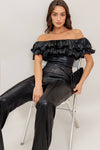 Off-the-shoulder black coated woven jumpsuit with ruffled sleeves and a fitted silhouette, perfect for Long Island boutique fashion.