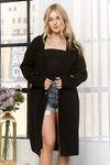 Classic longline black coat featuring button details, a tailored fit, and paired with a cropped top and denim shorts for a chic Long Island boutique fashion look.