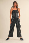 Striking black faux leather barrel strapless jumpsuit featuring a fitted bodice, wide-leg pants, and side pockets, perfect for Long Island boutique fashion.