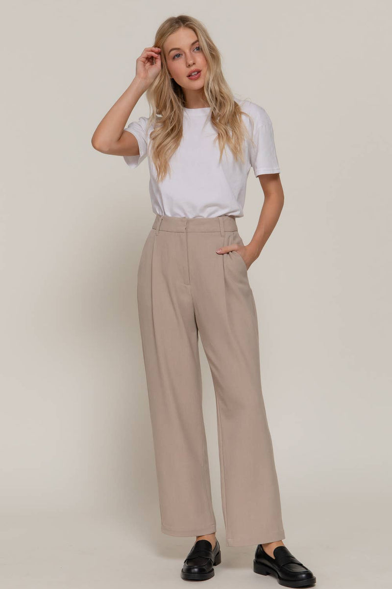Beige front pleat detail pants with a high waist and wide leg fit, perfect for stylish looks at a Long Island women's boutique.