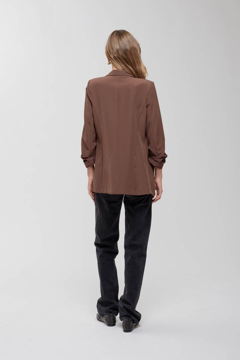 Stylish brown 3/4 ruched sleeve blazer, tailored fit, perfect for chic ensembles at a Long Island boutique fashion event.