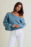 Cozy blue asymmetrical shoulder sweater top featuring balloon sleeves and ribbed hem, perfect for casual wear from a Long Island women’s boutique.
