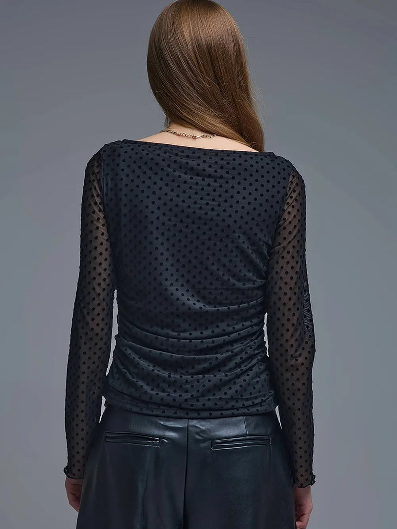 Sheer black polka dot top with long sleeves and ruched detailing, perfect for layering in Long Island boutique fashion.