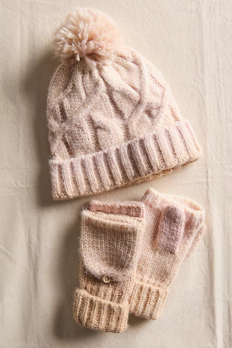 Cozy knitted hat with a pom-pom and matching fingerless gloves in soft pastel pink, perfect for Long Island boutique fashion enthusiasts.