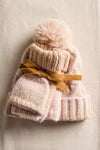 Cozy pink knit hat with a fluffy pom-pom and matching gloves, adorned with a golden ribbon, perfect for Long Island boutique fashion.