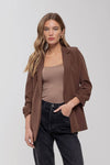Chic brown 3/4 ruched sleeve blazer paired with a nude top and black high-waisted jeans, perfect for Long Island boutique fashion.