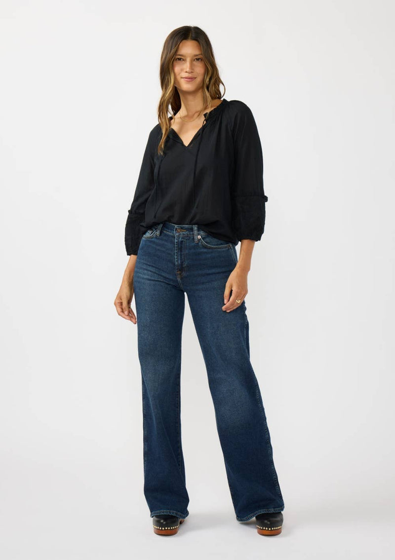 Flowy black blouse with frilled sleeves and a split neck, perfectly styled with high-waisted flared jeans in this Long Island boutique fashion look.