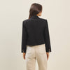 Cropped black flap-pocket jacket with tailored shoulders and buttoned cuffs, perfect for chic layering in Long Island boutique fashion.