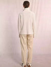 Chunky cable knit turtleneck sweater in a soft cream color, paired with relaxed beige trousers, perfect for cozy Long Island boutique fashion.