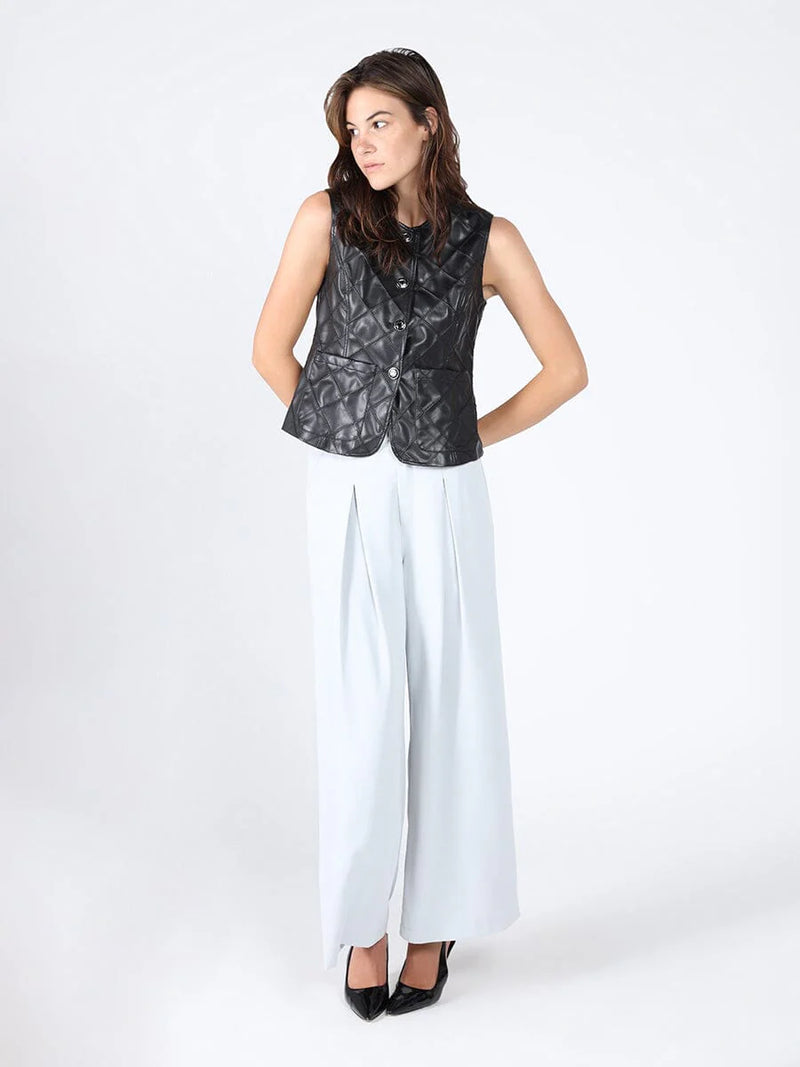 Quilted black leather crew neck vest featuring a fitted silhouette, styled with wide-leg trousers for a chic Long Island boutique fashion look.