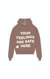Relaxed-fit brown hoodie featuring bold white lettering that reads "YOUR FEELINGS ARE SAFE HERE," a cozy Long Island boutique fashion choice.