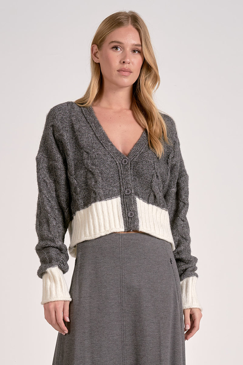 Cozy two-tone sweater cardigan in dark gray and cream, featuring a cable knit pattern and cropped fit, perfect for Long Island boutique fashion.