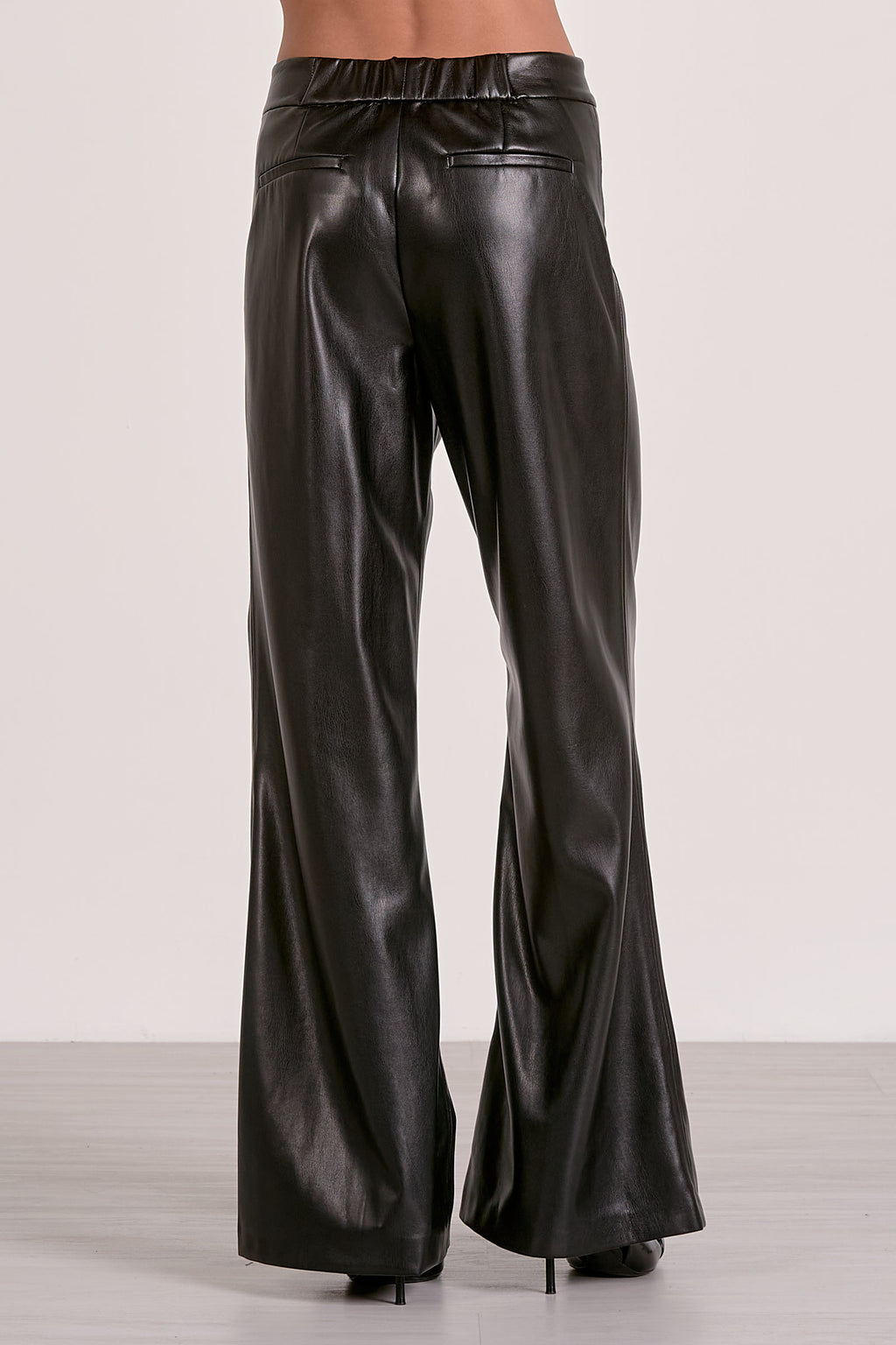 Sleek black high-waisted flare pants with a smooth faux leather finish, ideal for chic looks in Long Island boutique fashion.