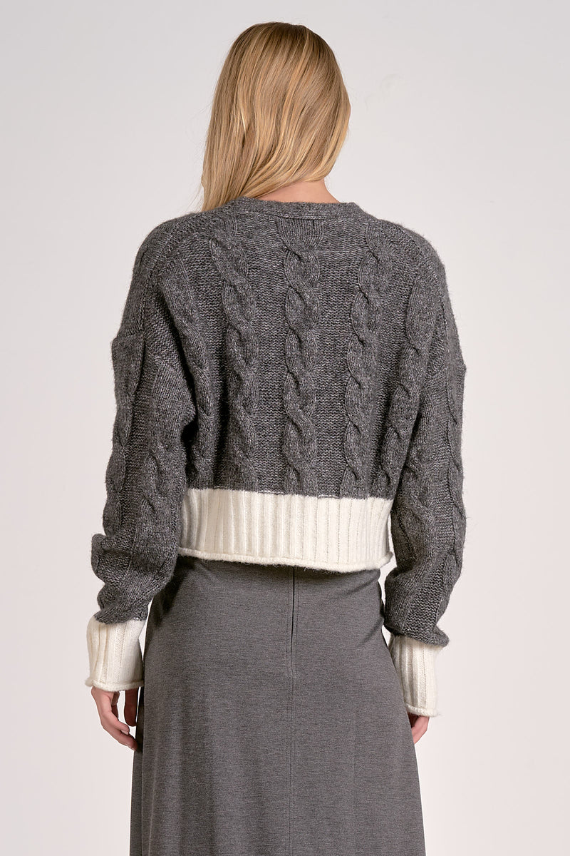 Cozy dual-tone sweater cardigan in gray with a ribbed white waistband and intricate cable knit design, perfect for Long Island boutique fashion.