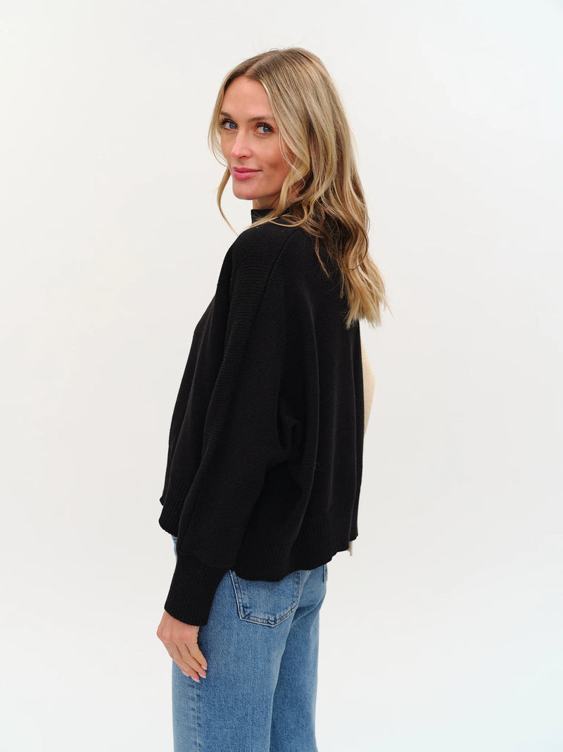 Soft black colorblock sweater with an uneven hem, featuring a relaxed fit and ribbed cuffs, perfect for Long Island boutique fashion.